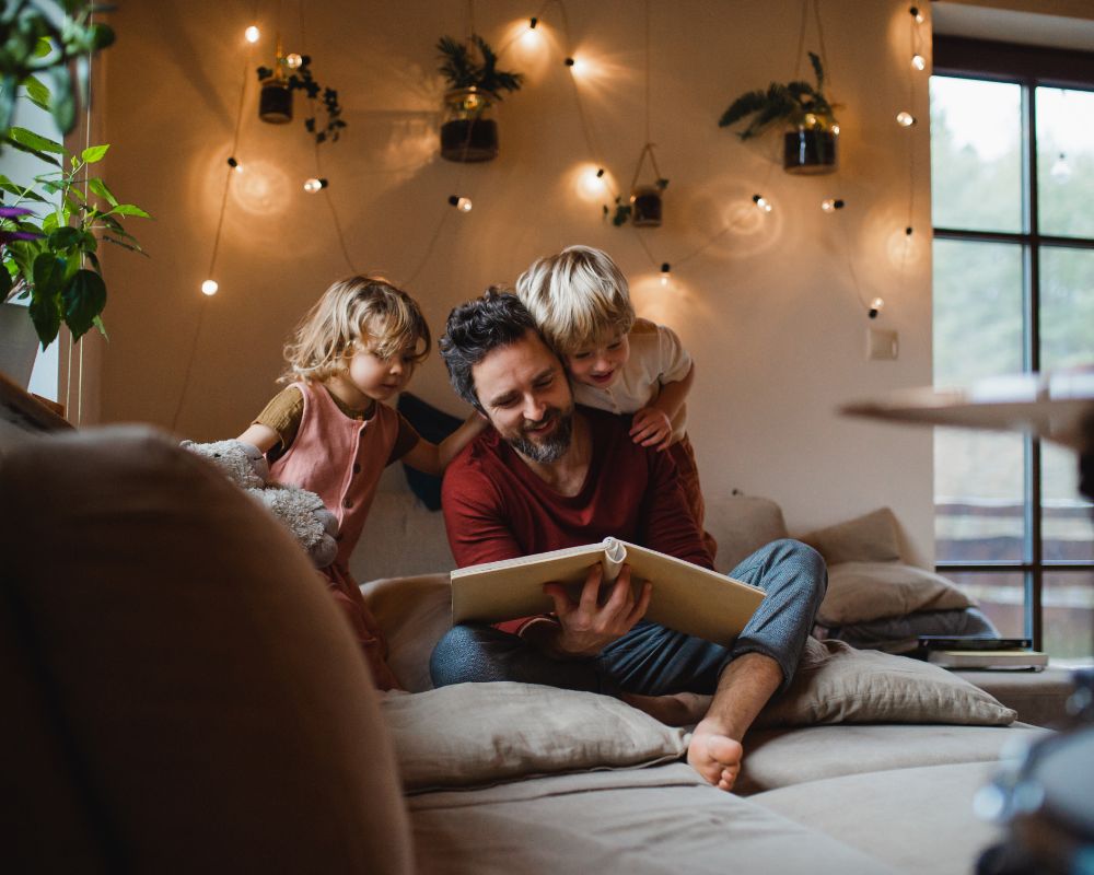 Gemütliche Stunden zu Hause mit der passenden Wärmelösung Vater und Kinder genießen gemeinsam die Wärme auf der Couch